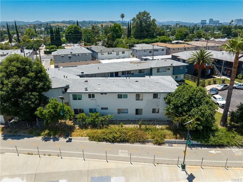 A street view of a residential area with apartment buildings and palm trees.