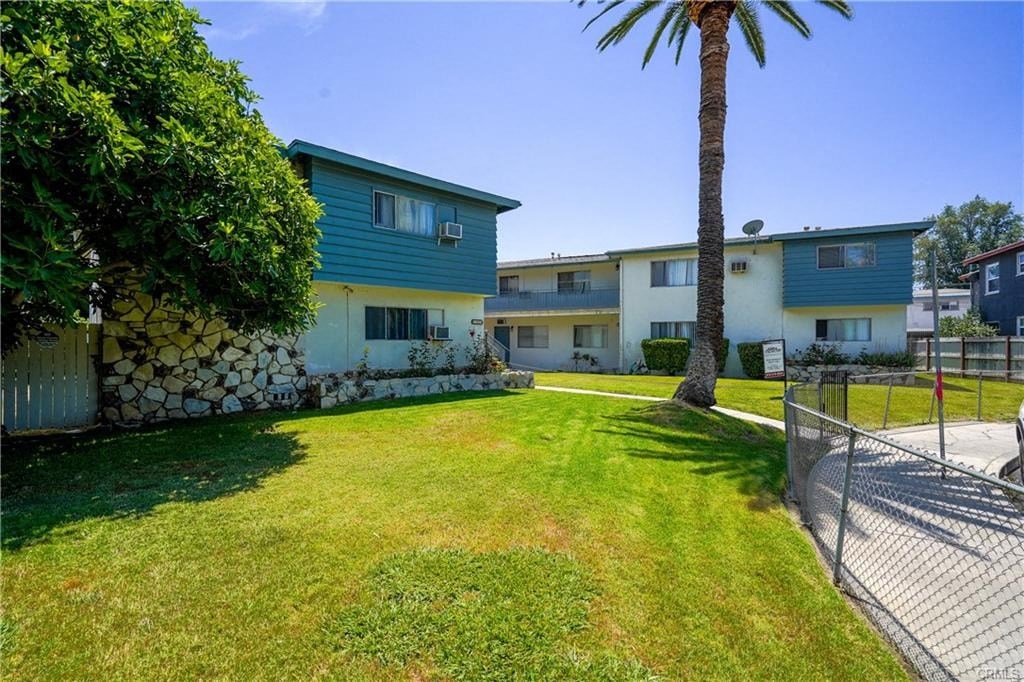 A palm tree stands in a grassy yard in front of a building.