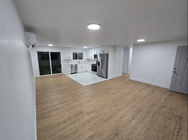 A spacious room with wooden flooring and white walls.