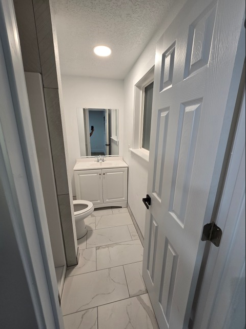 A white bathroom with a toilet, sink, and medicine cabinet.