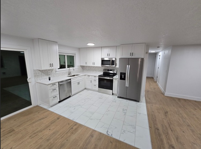 A kitchen with white cabinets and a white tiled floor.