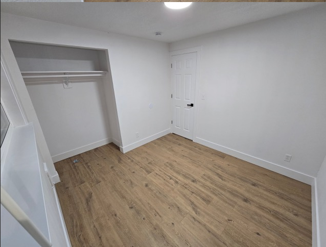 A room with wooden flooring and white walls.
