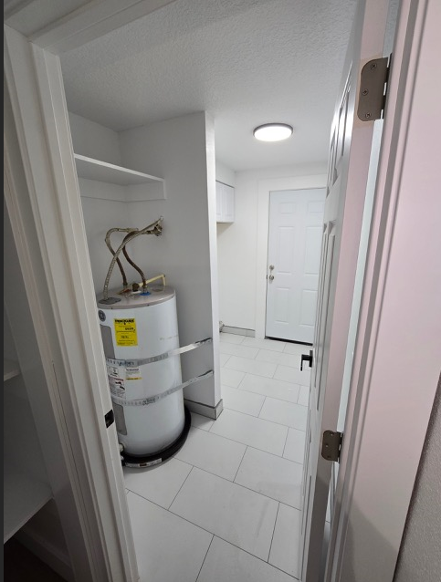 A white refrigerator with a yellow sticker on it is in a narrow hallway.