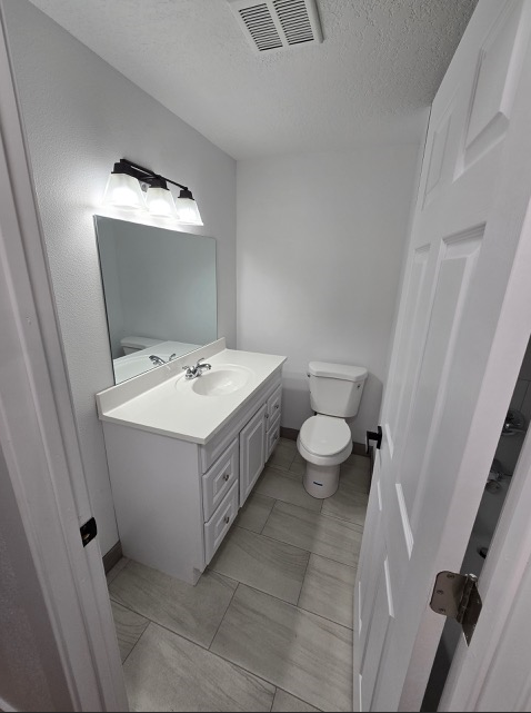 A white bathroom with a toilet, sink, and mirror.