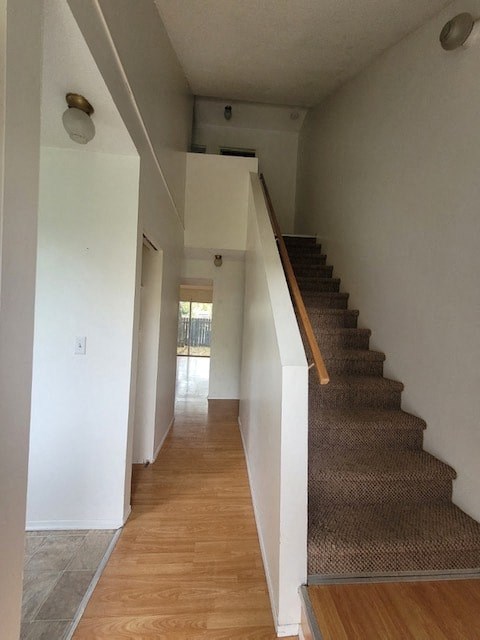 A staircase with a brown carpeted runner and wooden steps.