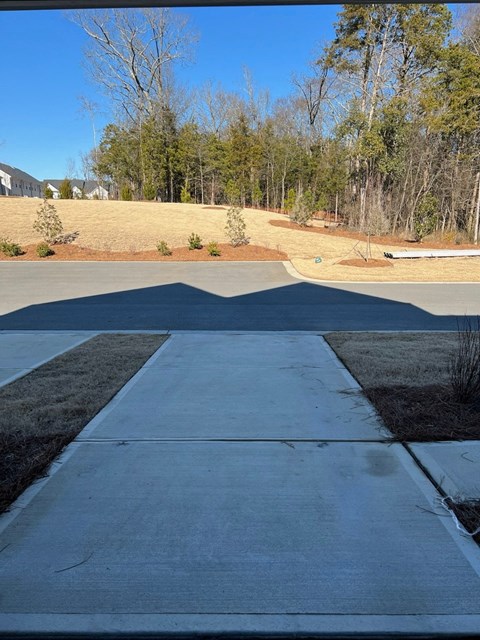 A long concrete walkway leads to a grassy area.