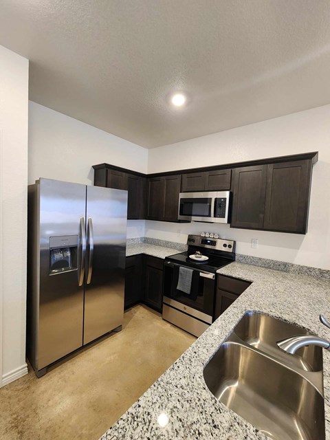 A kitchen with a stainless steel refrigerator, microwave, and oven.