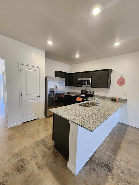A kitchen with a granite countertop and black cabinets.