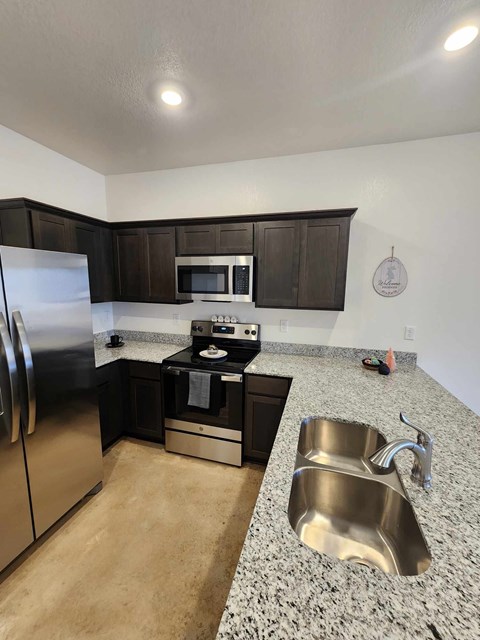 A kitchen with a stainless steel refrigerator, microwave, oven, and sink.