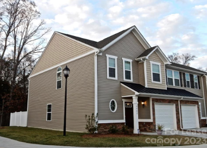 a house with brown siding and white garage doors