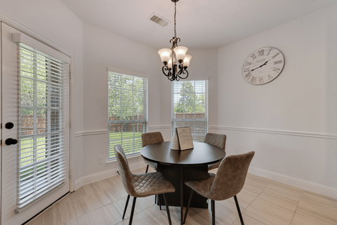 a dining room with a table and chairs and a clock on the wall