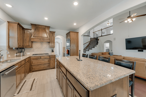 the kitchen has a large island with granite counter tops and wooden cabinets