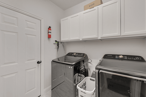 a laundry room with white cabinets and a washer and dryer