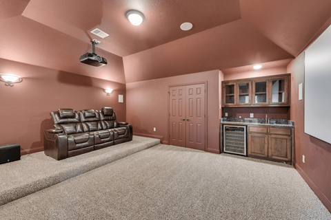 a bonus room with a leather couch and a kitchen