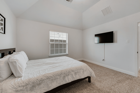 a bedroom with a bed and a tv on the wall