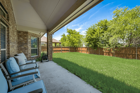 the patio of a home with a lawn and chairs