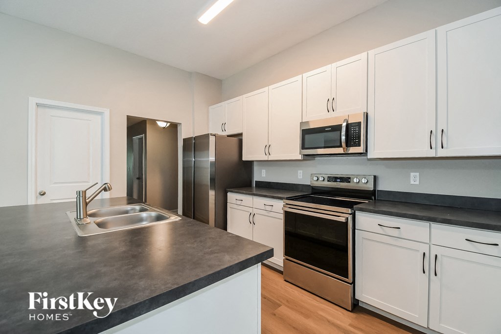 a kitchen with white cabinets and stainless steel appliances and a sink