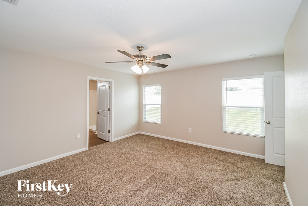 an empty living room with a ceiling fan and a carpet
