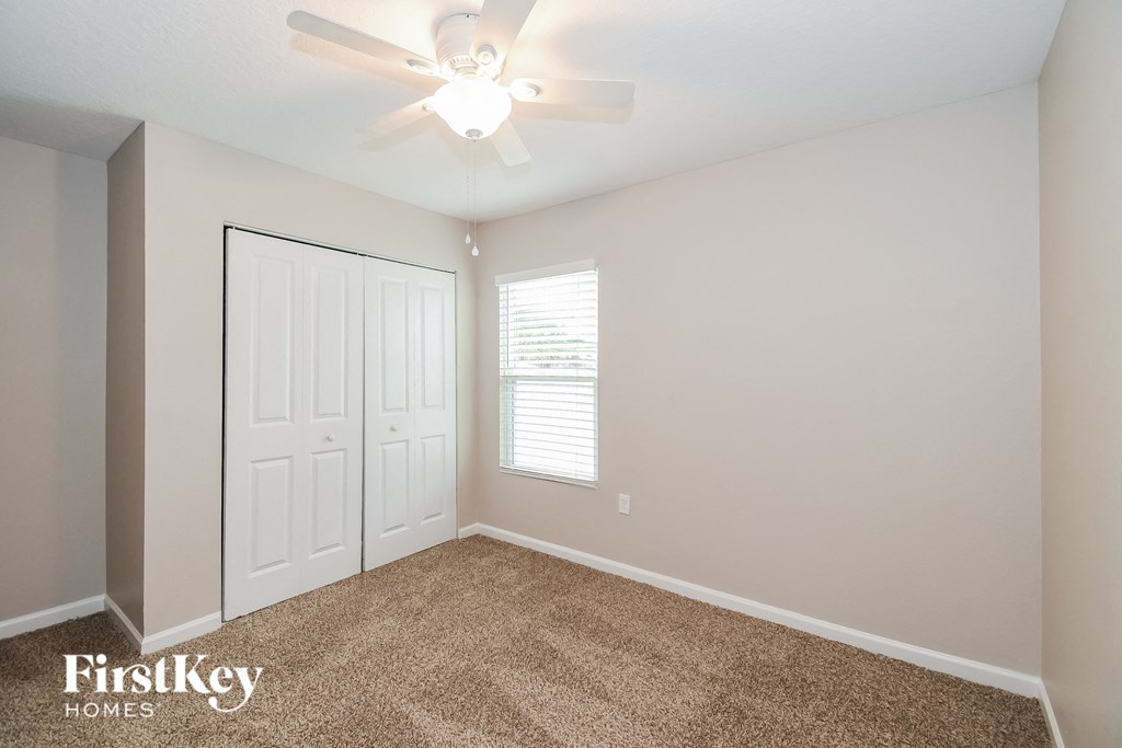 a bedroom with a ceiling fan and a closet