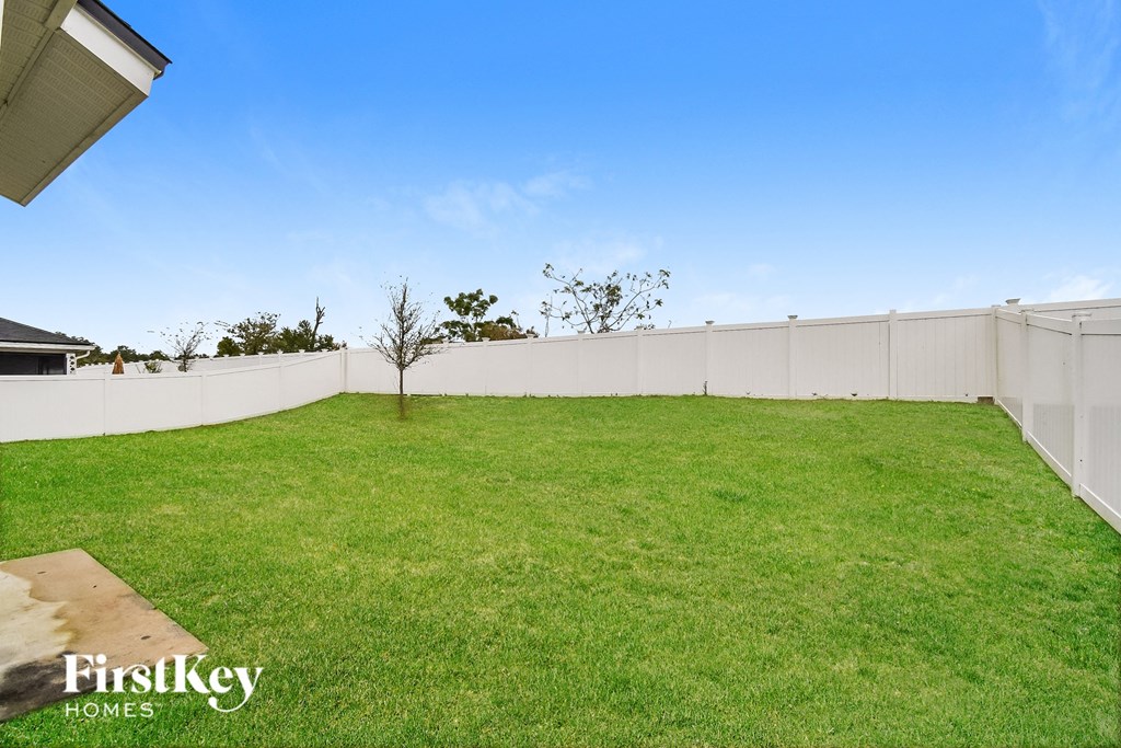 a backyard with green grass and a white fence