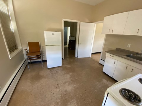 a kitchen with white cabinets and appliances and a dirty floor