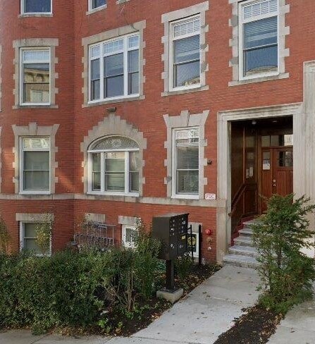 A red brick building with a black mailbox and a brown door.
