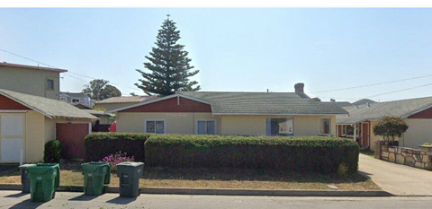 A house with a red roof and a green hedge in front.