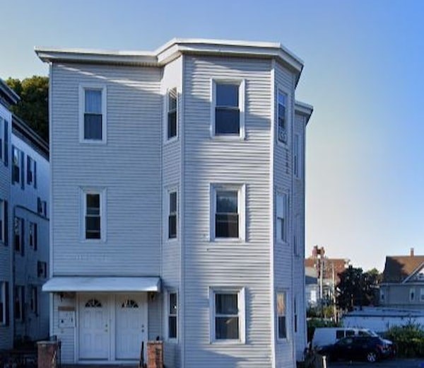 A two-story residential building with a white exterior and a garage door.