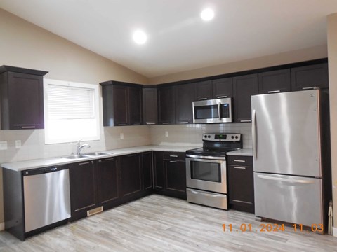 A kitchen with dark brown cabinets and stainless steel appliances.