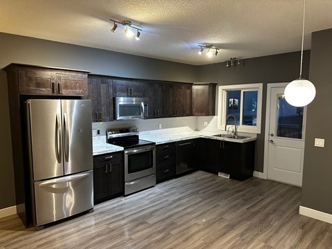 A modern kitchen with dark wood cabinets and stainless steel appliances.
