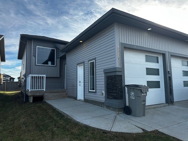 A grey house with a white door and a grey trash bin in front.
