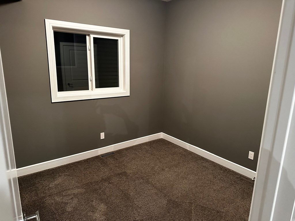 A room with a window and carpeted floor.