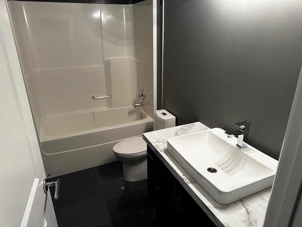 A white sink is on a counter next to a toilet.
