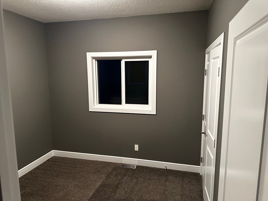A room with a carpeted floor and a window.