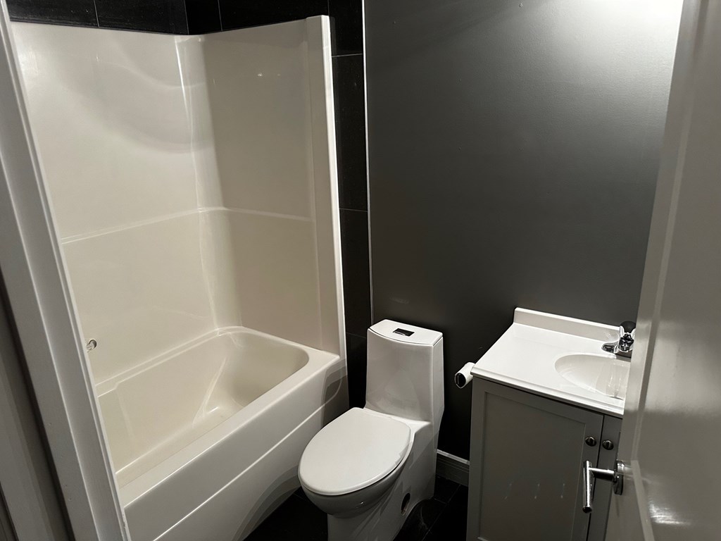 A white toilet sits next to a white sink in a small bathroom.