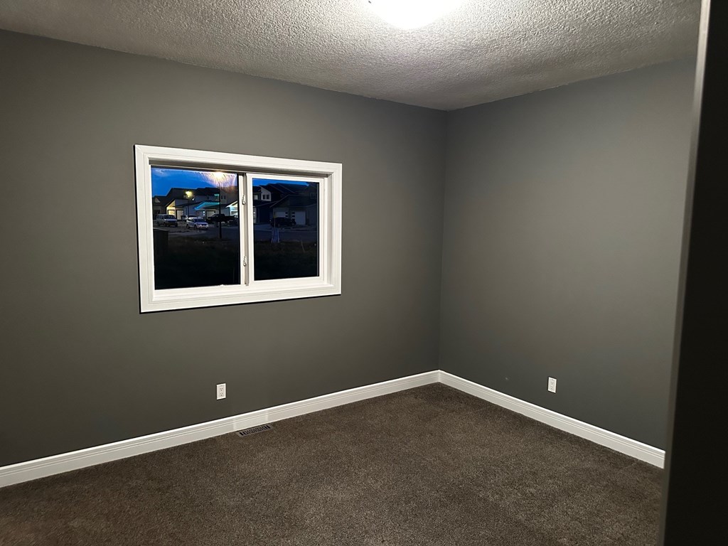 A room with a window showing a view of a street with houses.