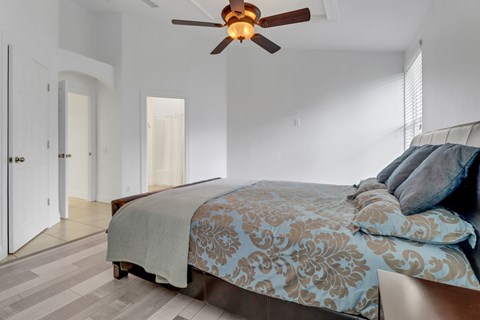 A bedroom with a bed and a ceiling fan.