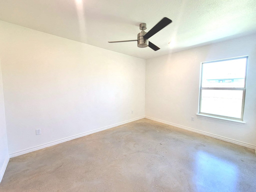 an empty room with a ceiling fan and a window