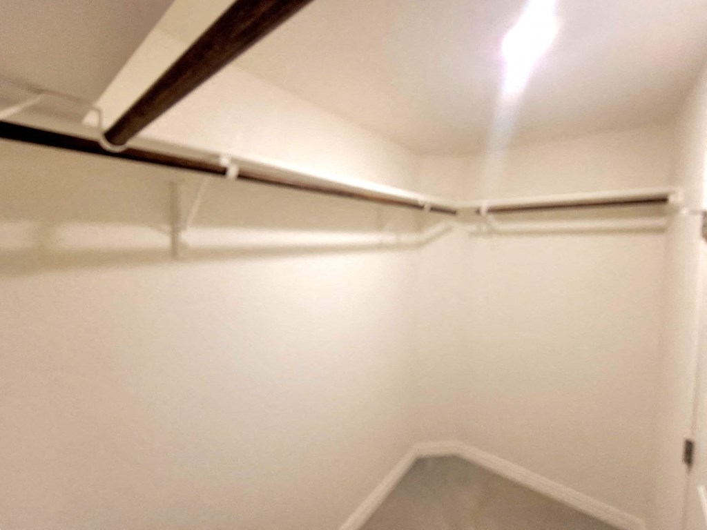 an empty basement room with white walls and a pipe on the ceiling