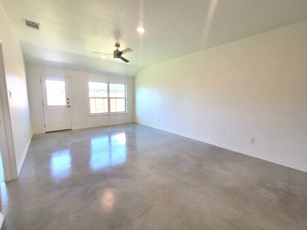 an empty living room with white walls and a ceiling fan
