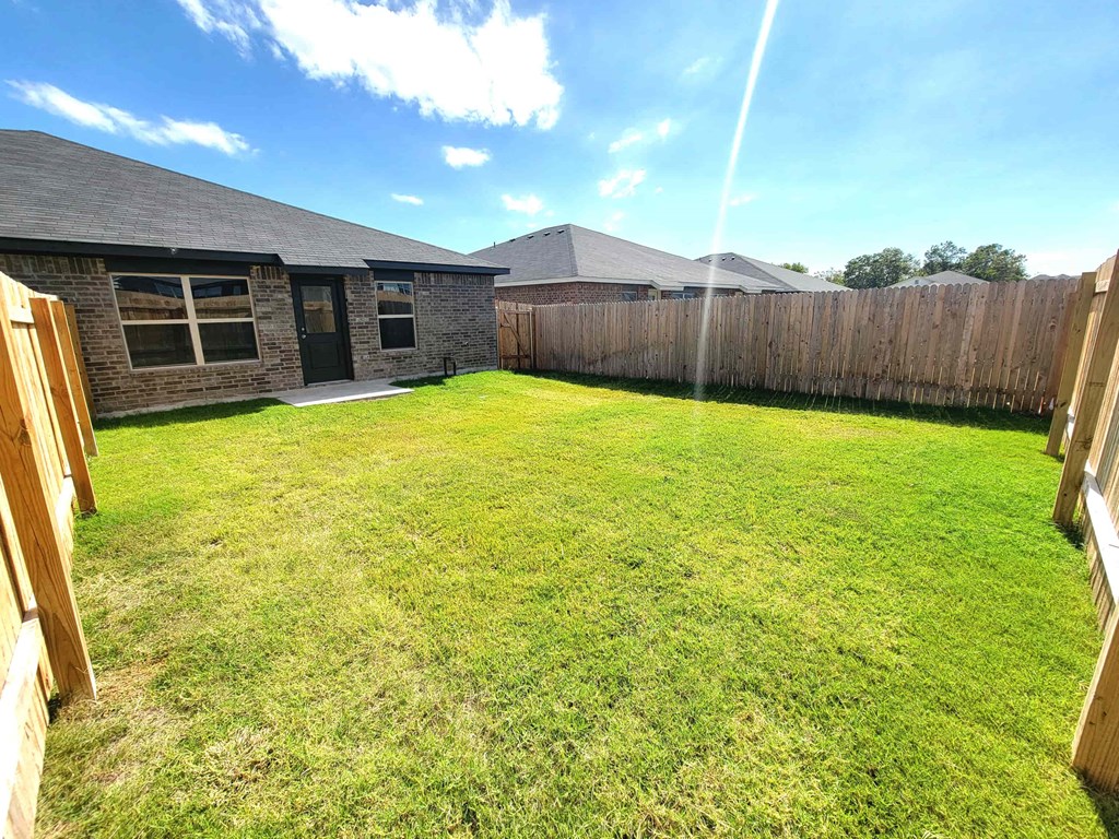 a backyard with a fence and a yard and a house