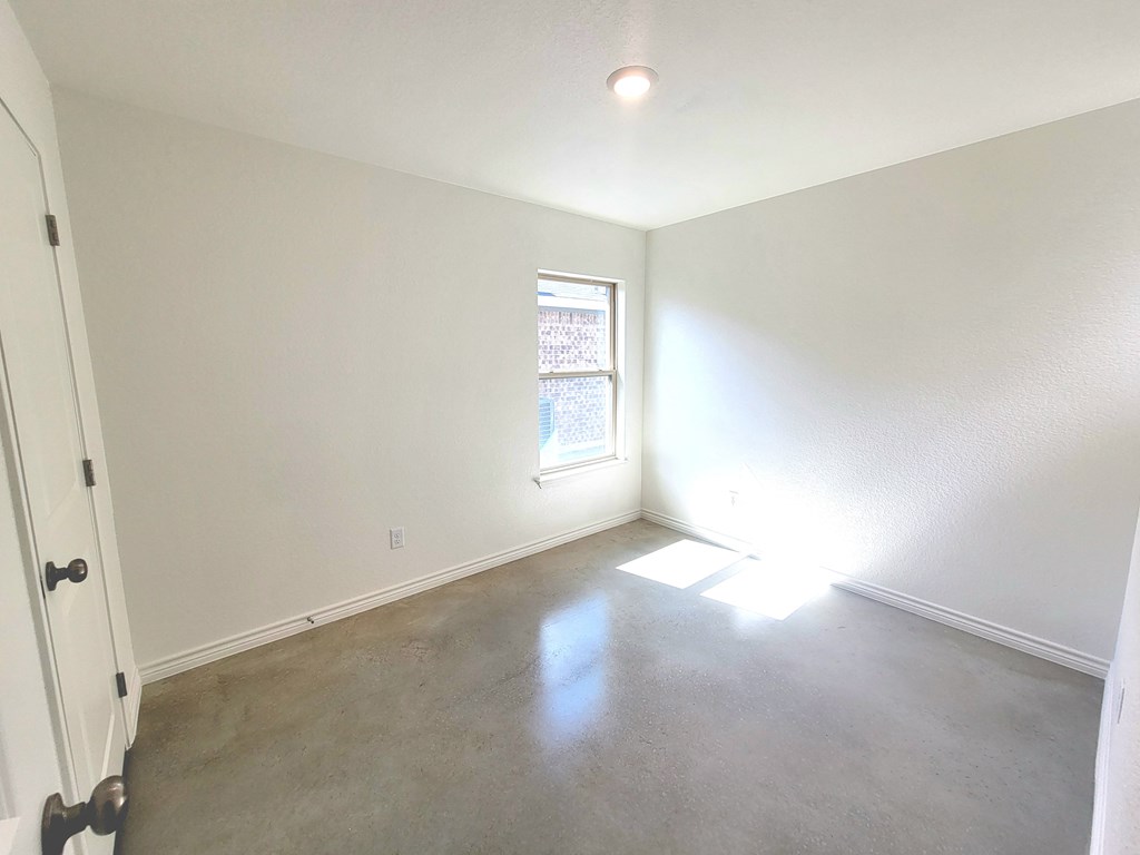 an empty living room with white walls and a window