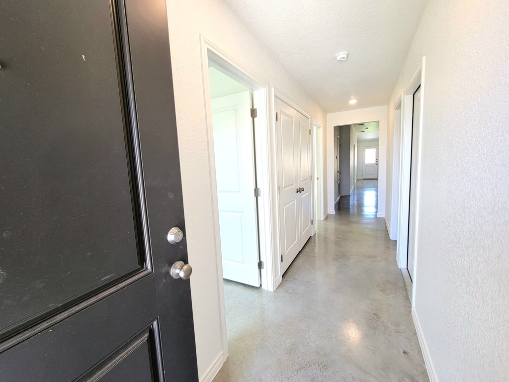 a long hallway with black doors and white walls and a cement floor