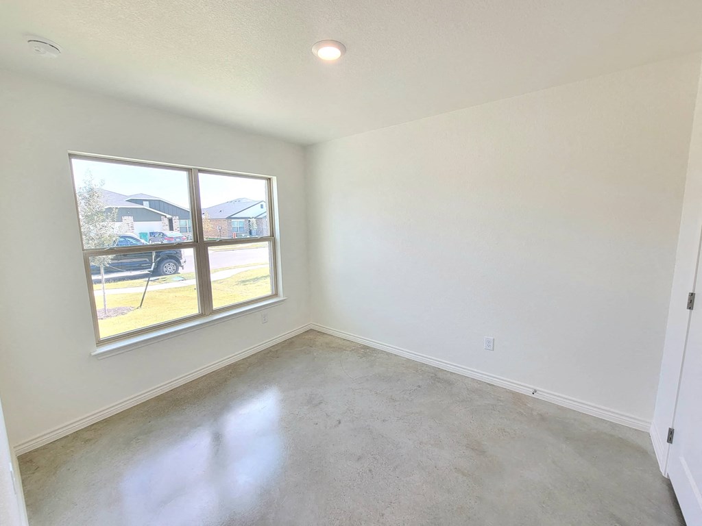 an empty living room with a window and concrete floor