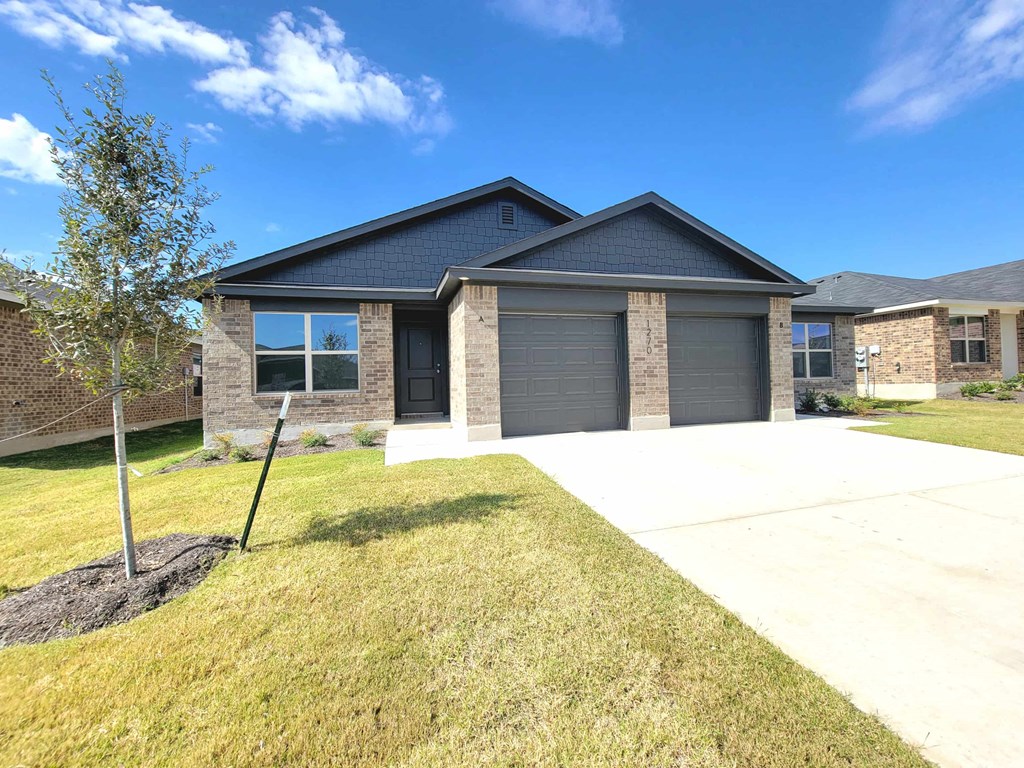 a house with a driveway and a tree in front of it