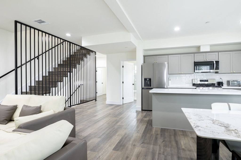 a living room with a staircase and a kitchen