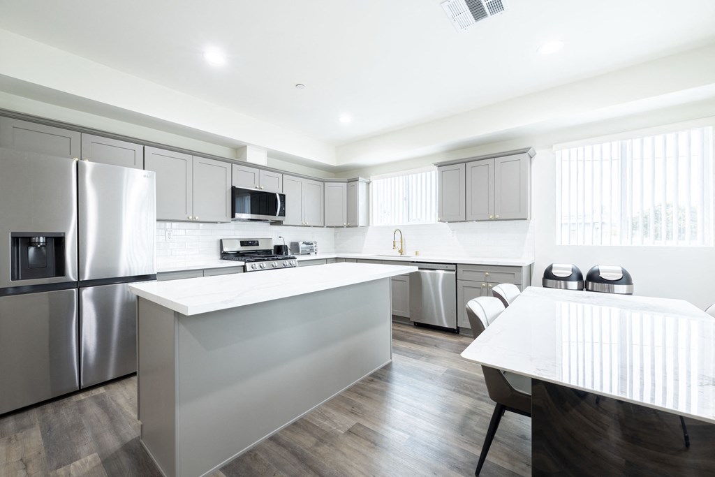 a large kitchen with stainless steel appliances and a white counter top