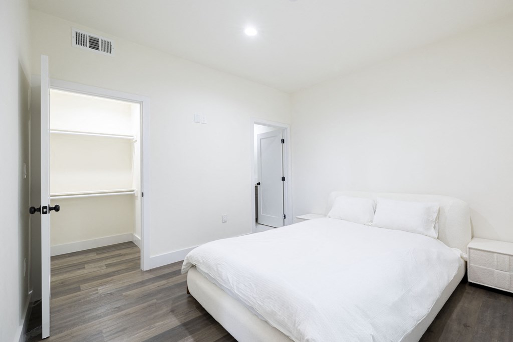 a white bedroom with a white bed and a white closet