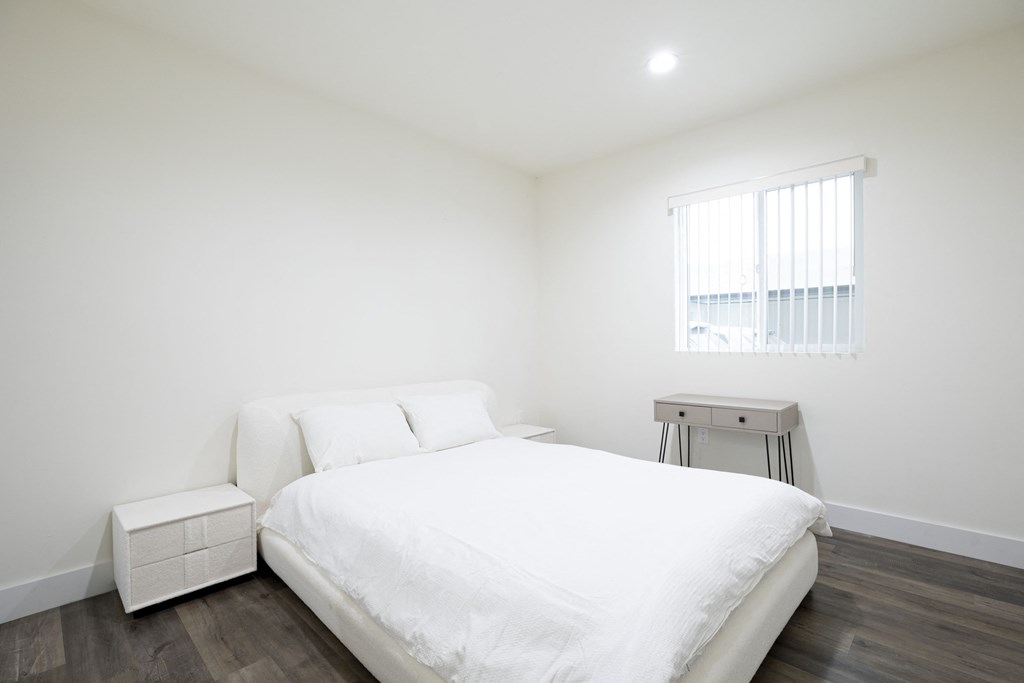 a white bedroom with a white bed and a table
