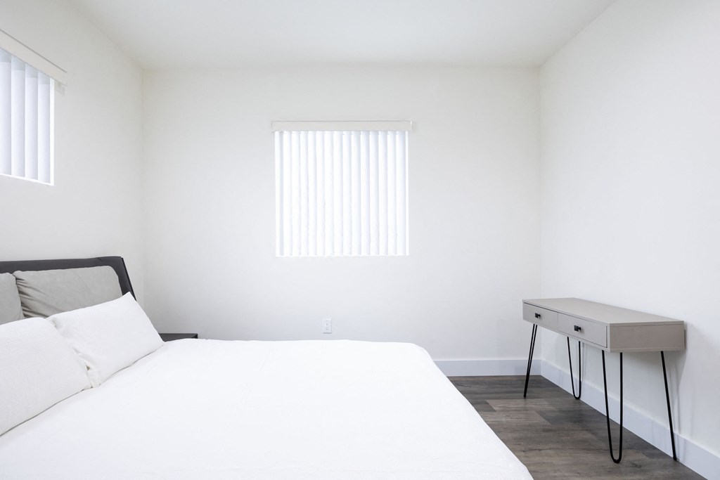 a white bedroom with a bed and a desk